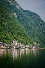Fototapeta na wymiar Travel to the Alps. City Hallstatt. City among the mountains in the Alps. Hallstatt is beautiful small town in Austria. town is reflected in the water on a sunny day 
