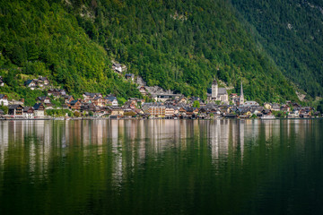 Fototapeta na wymiar Travel to the Alps. City Hallstatt. City among the mountains in the Alps. Hallstatt is beautiful small town in Austria. town is reflected in the water on a sunny day 