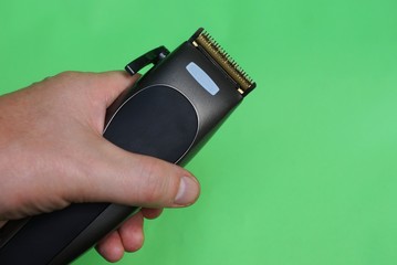 electric black clipper in hand on a green background