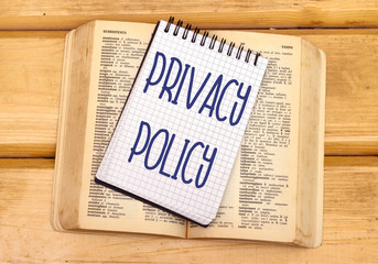 privacy police in notebook on open old book in wooden table