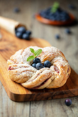 Pleated bun with blueberry and mint on wooden cutting board, vertical composition