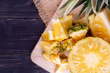 Fresh pineapple on black wood, black background.