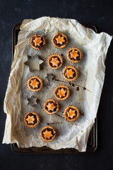 Freshly baked mince pies on a tray with festive star shaped cookie cutter. Overhead view