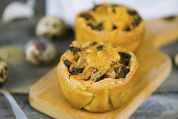 Baked puff pastry with meat stuffing and cheese on a wooden board