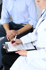 Female doctor holding application form while consulting man patient in hospital. Medicine and...