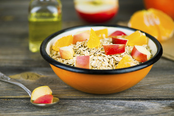 oatmeal with fruit, apple and mandarin on a wooden board