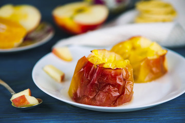 Baked apple with cheese on a plate on a wooden board