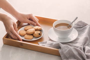 Hand putting cookies on plate into tray. Breakfast concept with coffee