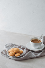 Closeup of coffee with milk in white cup and tasty cookies. Shot on light stone background