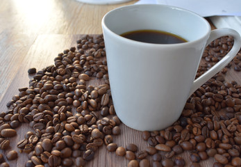 White cup with coffee in coffee beans