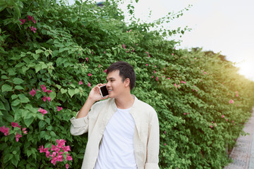 Handsome young man talking on the phone while walking on the street