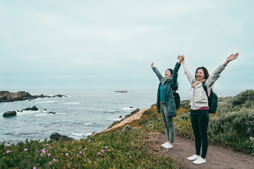 friends raising arms standing on the coast