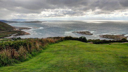 A landscape of a cloudy stormy sea and a grass lawn from Parque de Bens in Galicia capital city La Coruña