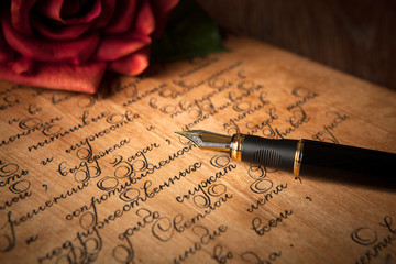 fountain pen on letter with text and red rose on a table
