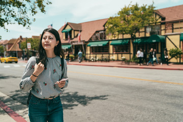 girl looking around while using phone and walking