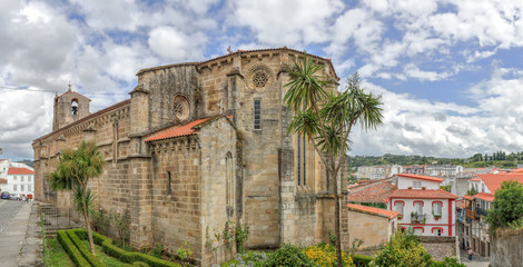 A landscape with the Santa Maria del Azogue church (Iglesia de Santa Maria del Azogue), some palm trees and a blue cloudy sky in the Betanzos city in Galicia, Spain