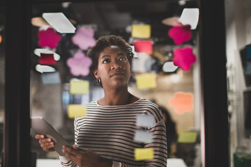 African American female brainstorming ideas at night in an office