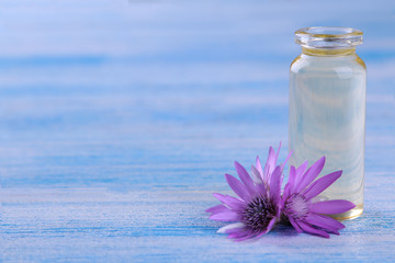 lilac field flowers with a bottle of essential oil on a blue wooden table with a place for writing