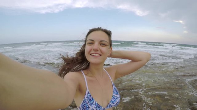 Cute girl taking selfie on the phone on the beach