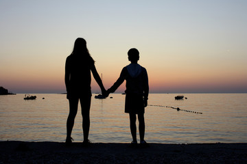 SILUETTA DI DUE RAGAZZI DURANTE IL TRAMONTO