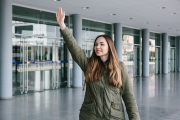 A beautiful positive girl welcomes someone on the street or waves a taxi.