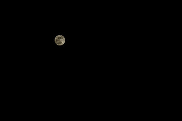Real snapshot of the full moon in a low key on a black background