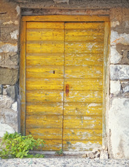Greece, wooden yellow door of traditional stone house