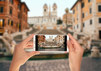 A tourist is taking a photo of Spanish Steps in the Plaza of Spain in Rome in the early morning...