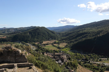 A landscape of cultivated fields, dense forest and mountains as seen from the ruins of the...