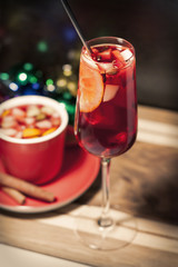 Бокал с горячим глинтвейном и красной чашкой с палочками корицы