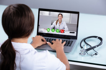 Fototapeta na wymiar Doctor Video Conferencing With Female Colleague On Laptop