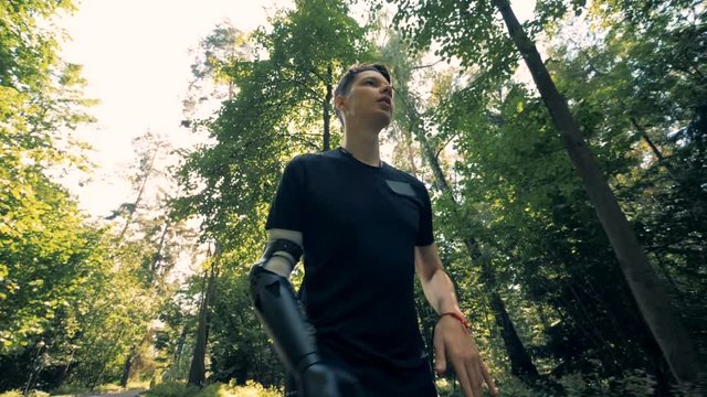 A man with an artificial arm is running along the alley. Futuristic human cyborg concept.