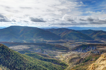 Blue cloudy sky and typical mountains and hills covered with forest met in autumn while hiking from...