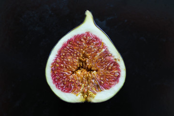 Fresh ripe fig cut in half over dark background, close up.