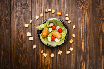 Obraz na płótnie Canvas Caesar salad with chicken, cherry tomatoes and quail eggs on a plate