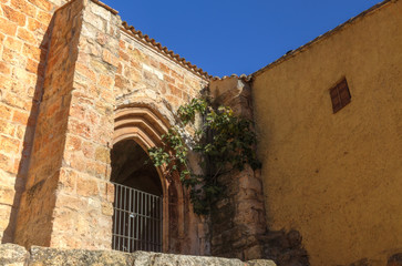 The entrance of the Saint Blaise church (Iglesia de San Blas) with a staircase, a pointed arch entrance and some climbing ivy in the Anento small town, in Aragon province, Spain