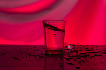 Glass of water in red background pouring honey