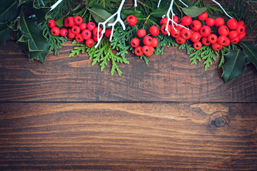 Wooden Christmas background with red berries as a border, copy space