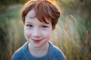 Cute curly boy, a sly look at the camera, close-up portrait.