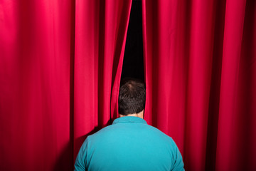 Man Peeking Through A Stage Curtain