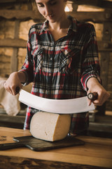 Obraz premium young woman cutting cheese with double handled knife