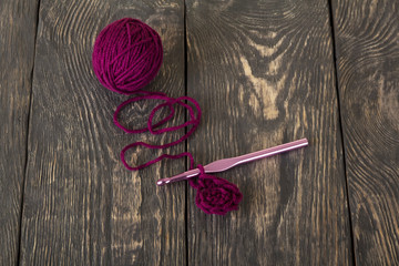 Purple wool thread for knitting and pink hook on beautiful dark boards