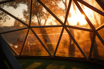 View from the transparent dome on the embankment of the Park at sunset in the orange rays of the sun.