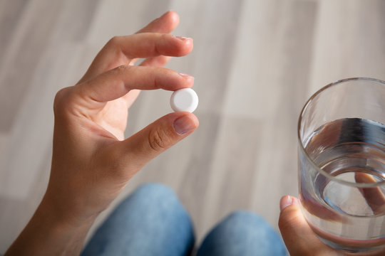 Woman With Glass Of Water Taking Medicine