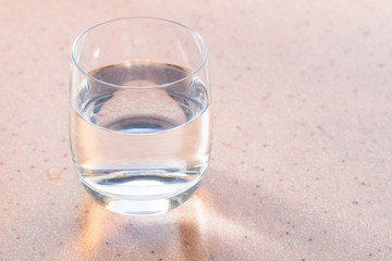 glass with clear water on pink board