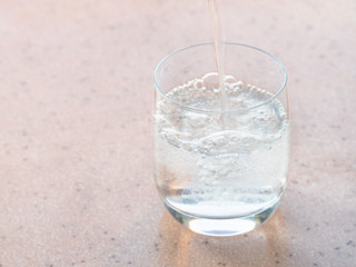 trickle of sparkling mineral water pours in glass