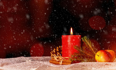 Kerze mit Weihnachtsdekoration und Schnee