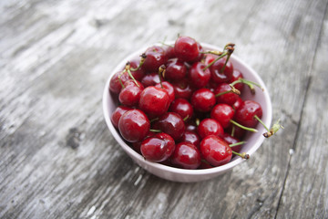 Bowl of cherries on a worn wooden background
