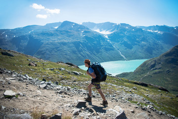 hiker with backpack walking on Besseggen ridge over Gjende lake in Jotunheimen National Park, Norway