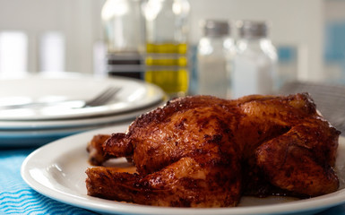 Grilled glazed chicken with table settings blurred in background